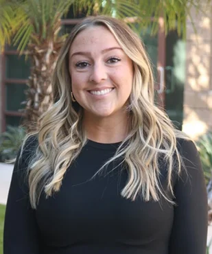 Kelsey, patient care coordinator, smiling in a professional outdoor portrait