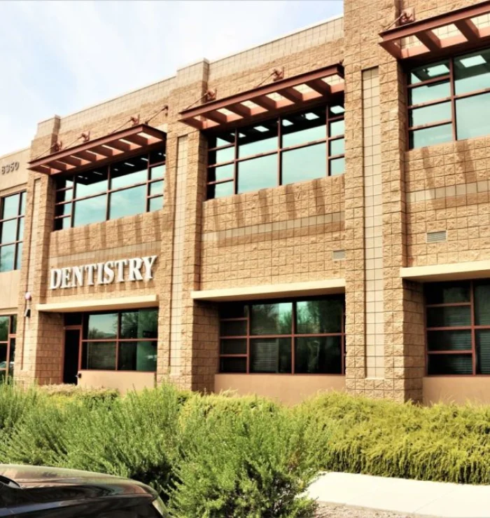 Exterior of the Belmont Dentistry office in Scottsdale, a two-story tan building with a “Dentistry” sign and landscaped shrubs out front