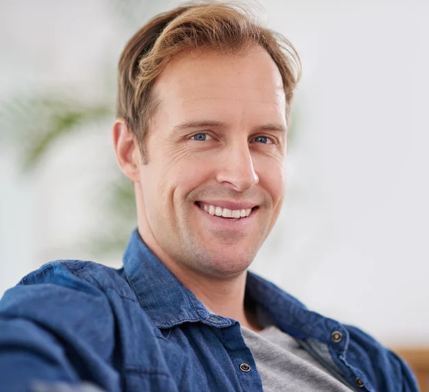 Smiling man wearing a blue shirt in a professional portrait