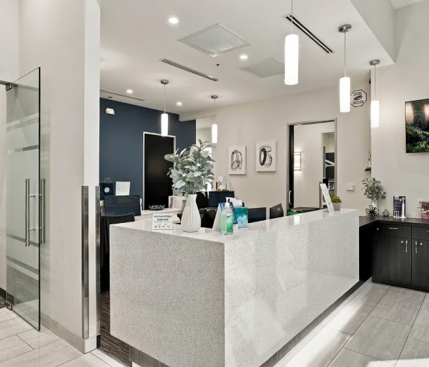 Modern dental treatment area with dental equipment, glass partitions, and bright overhead lighting.