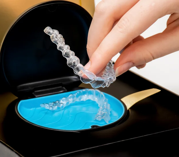 Hand placing a clear Invisalign aligner into its case